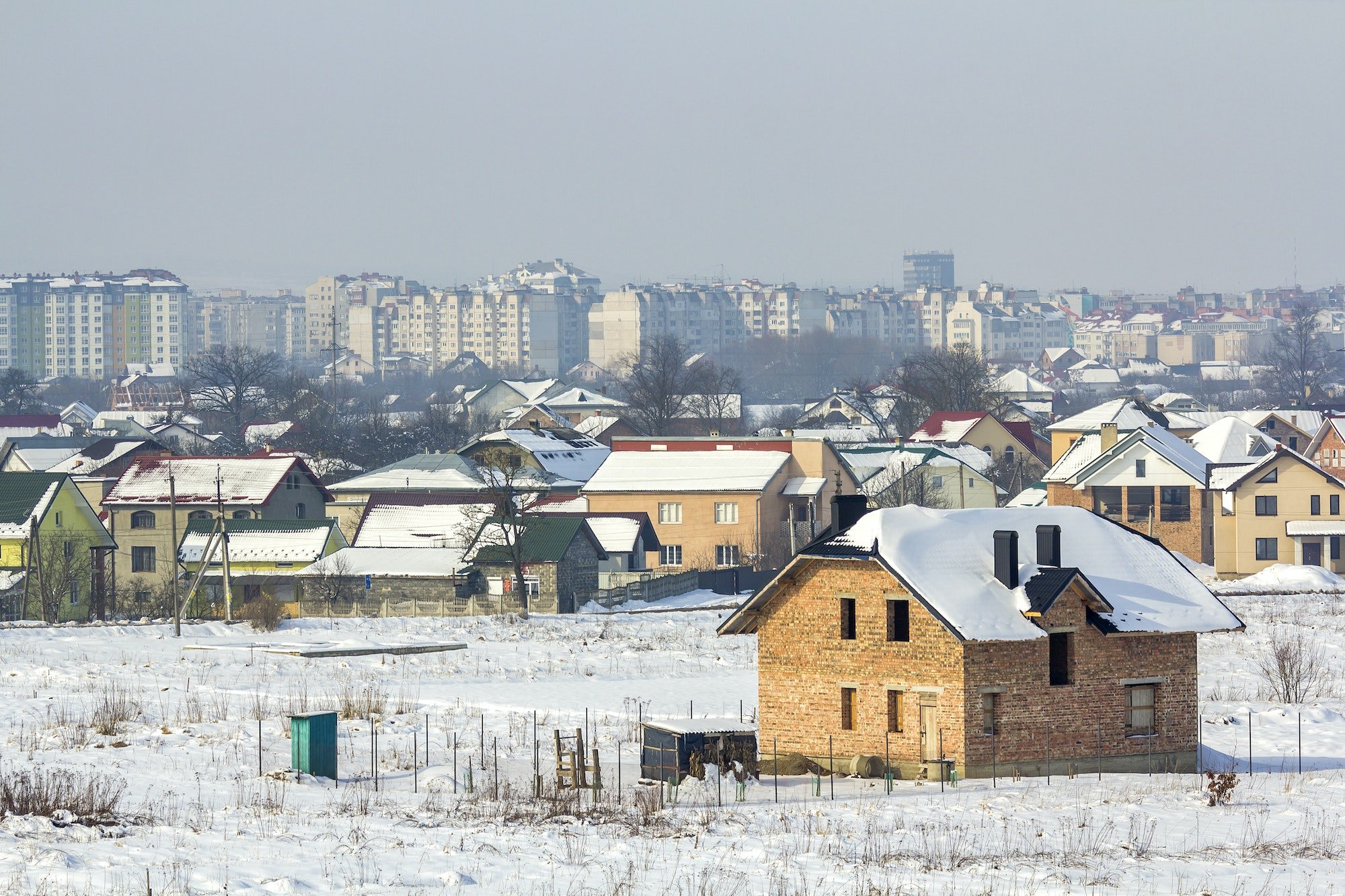 Wide winter panorama of rural land for development in quiet residential suburban area.